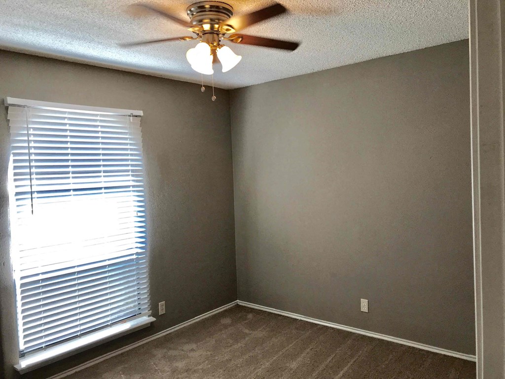 a bedroom with a large window and a ceiling fan