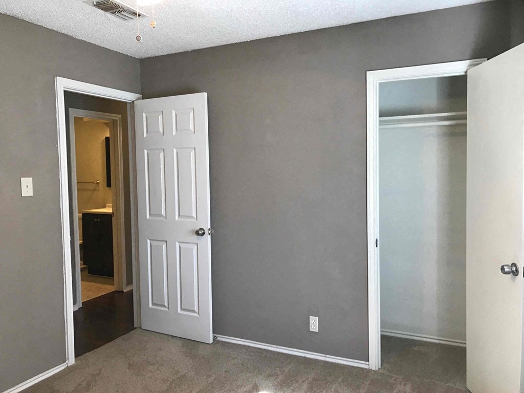 an empty room with a white door and a hallway to a bathroom