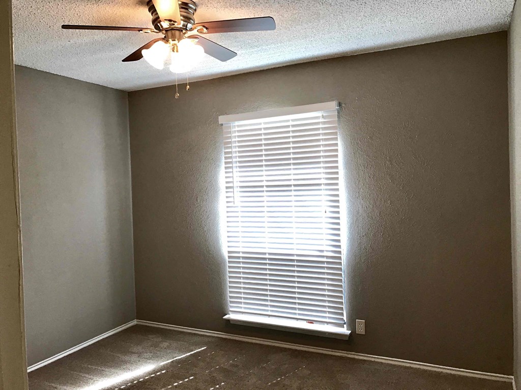 an empty room with a ceiling fan and a window