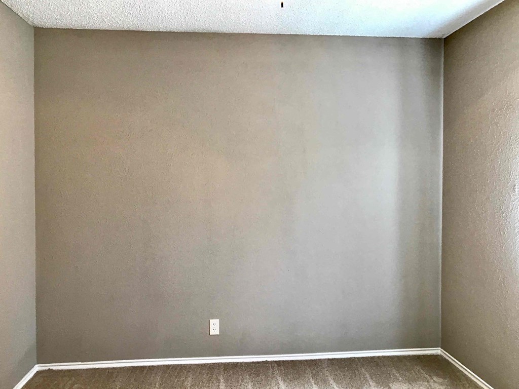 an empty room with a carpeted floor and grey walls