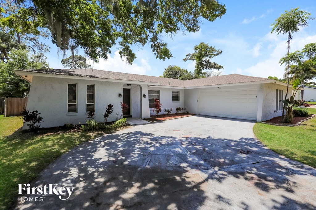 a white house with a driveway and a tree