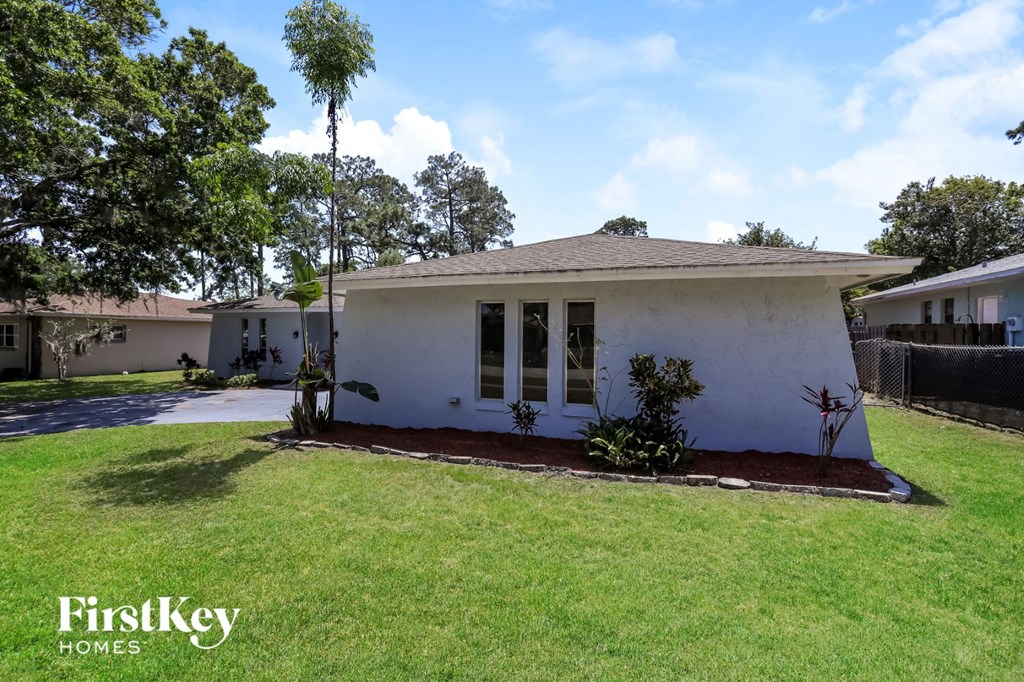 a small white house with a lawn and a driveway