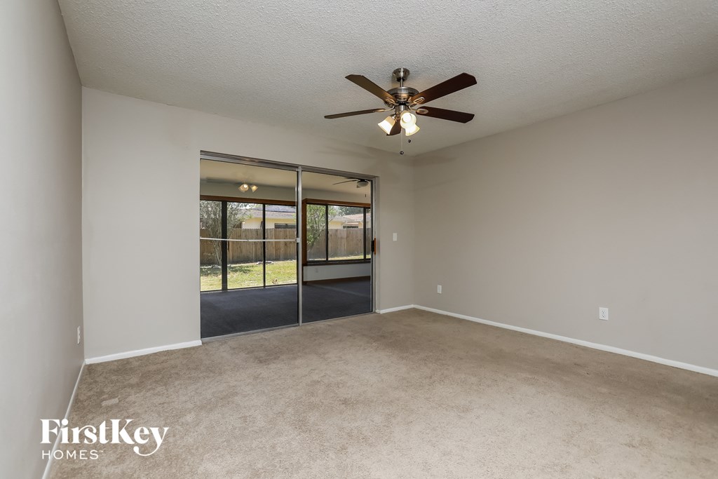 an empty living room with a ceiling fan and sliding glass doors