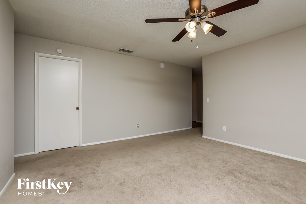 an empty living room with a ceiling fan and a closet