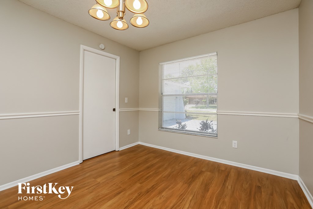 the living room of an empty house with wood flooring and a window