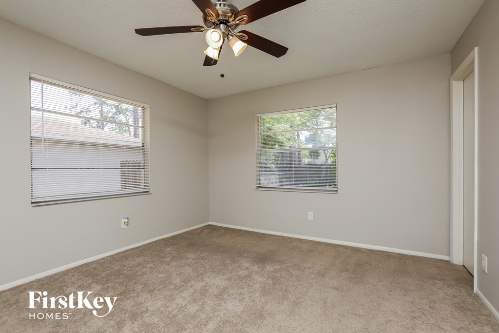 a bedroom with a ceiling fan and two windows