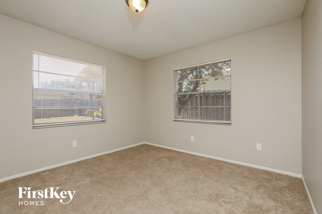a spacious room with two windows and a carpeted floor