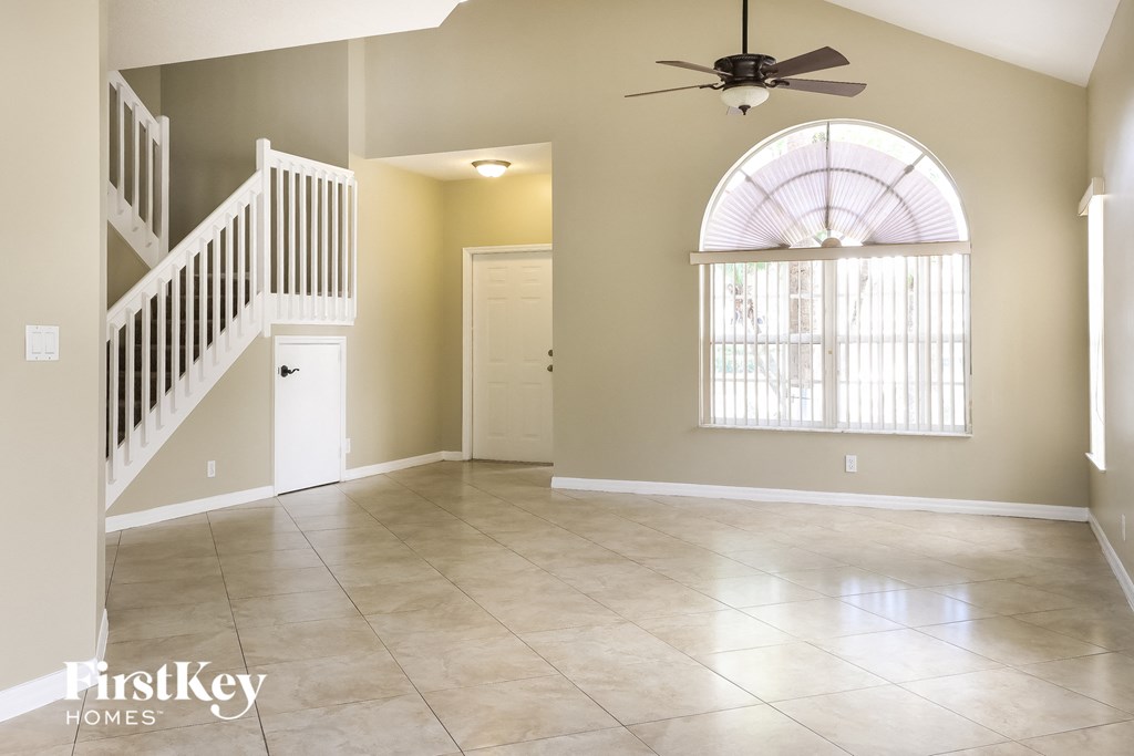 A spacious room with a fan and a staircase.