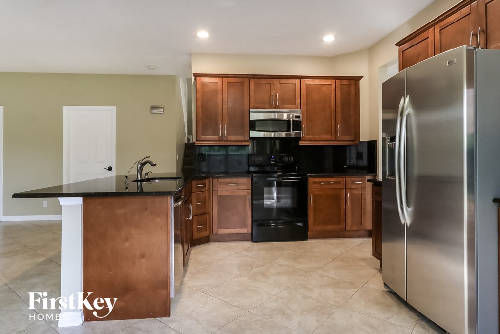 A kitchen with a black countertop and stainless steel appliances.