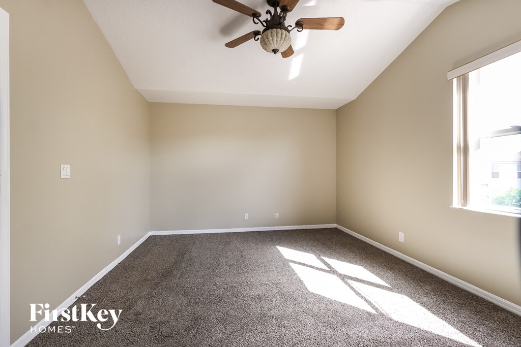A room with a ceiling fan and a window letting in sunlight.