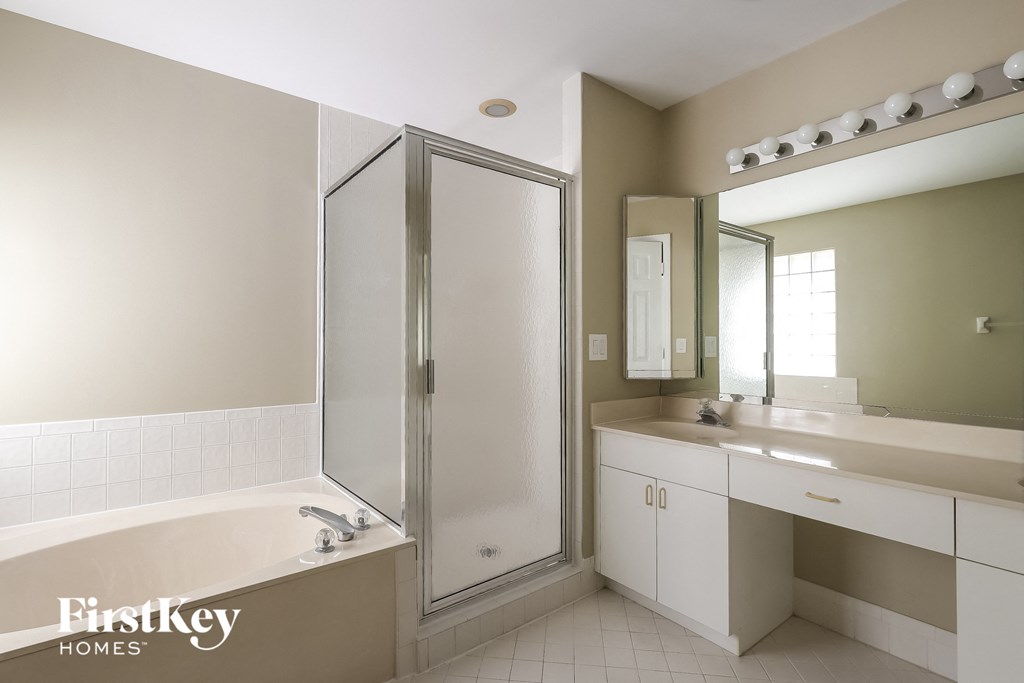 A bathroom with a tub, sink, and mirror.