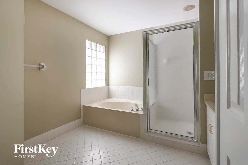 A clean, empty bathroom with a walk-in shower and a bathtub.
