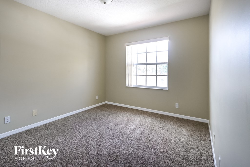 A room with a carpeted floor and a window with bars on it.