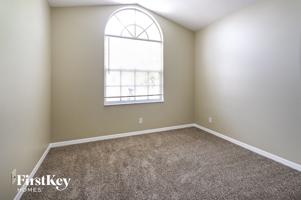 A room with a carpeted floor and a large arched window.