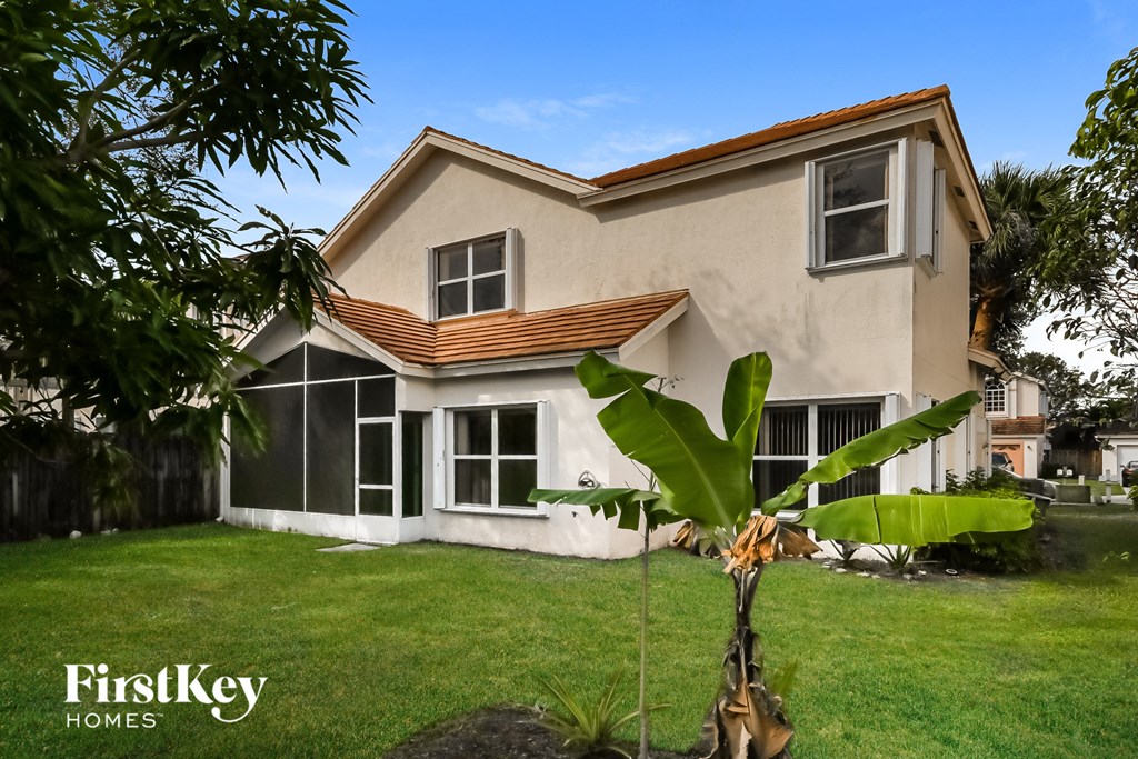 A house with a brown roof and a tree in front of it.