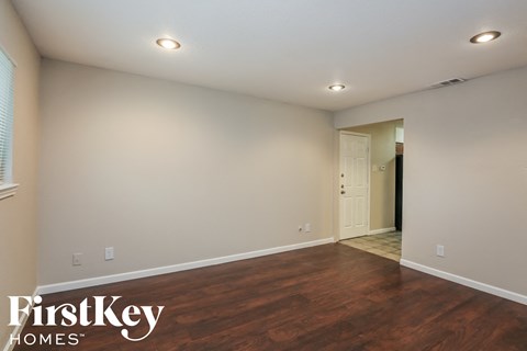 a living room with wood flooring and white walls and a white door