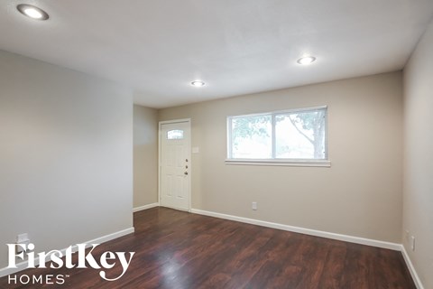 a room with white walls and wooden floors and a window and a door