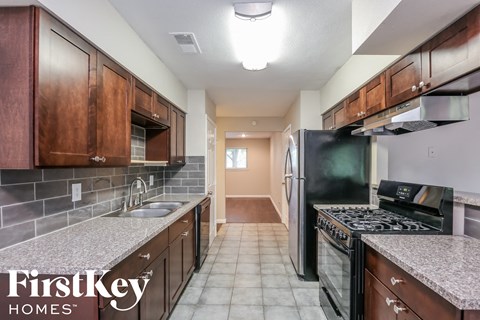 a kitchen with granite counter tops and wooden cabinets and black appliances
