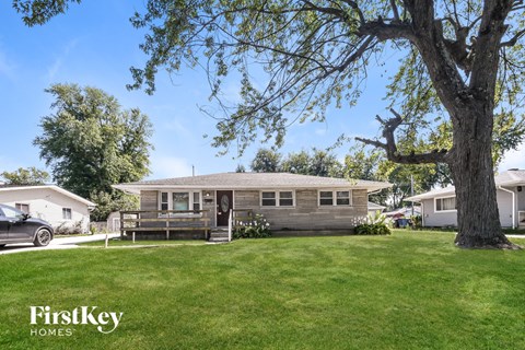 a bungalow with a large tree in front of it