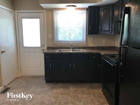 a kitchen with black cabinets and a sink and a door