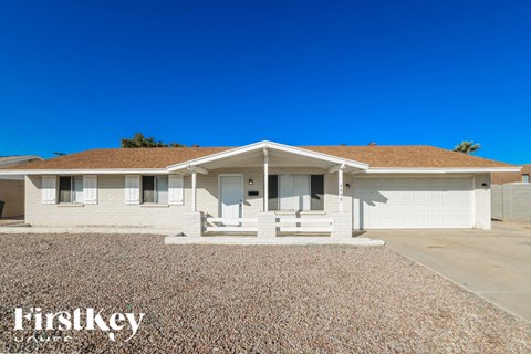 A house with a brown roof and a gravel driveway in front.