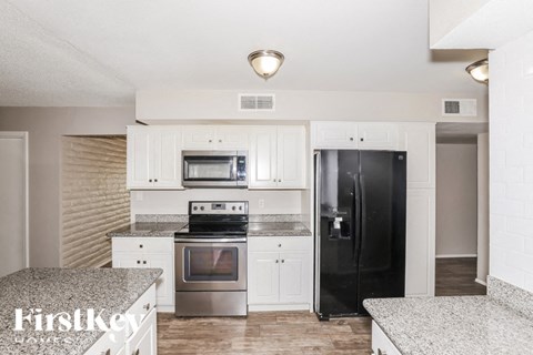 A kitchen with a black refrigerator and stainless steel appliances.