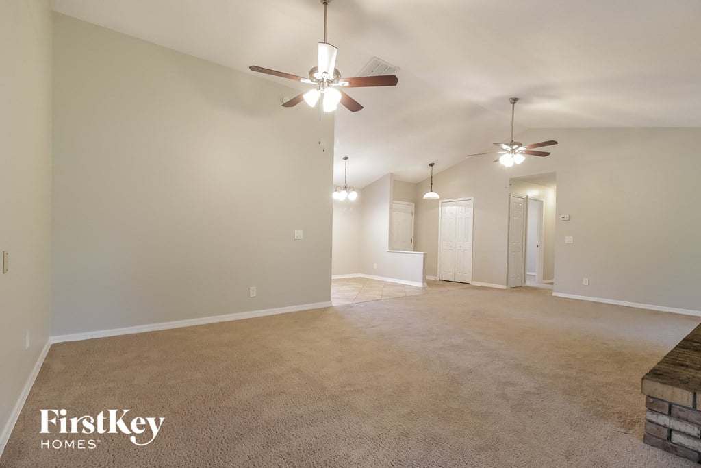 a spacious living room with a ceiling fan and a carpeted floor