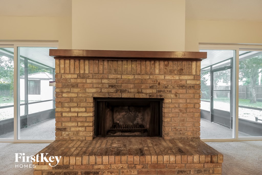 a brick fireplace in a living room with large windows