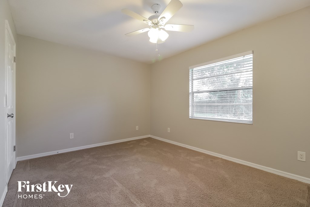 the master bedroom has carpeted floors and a ceiling fan