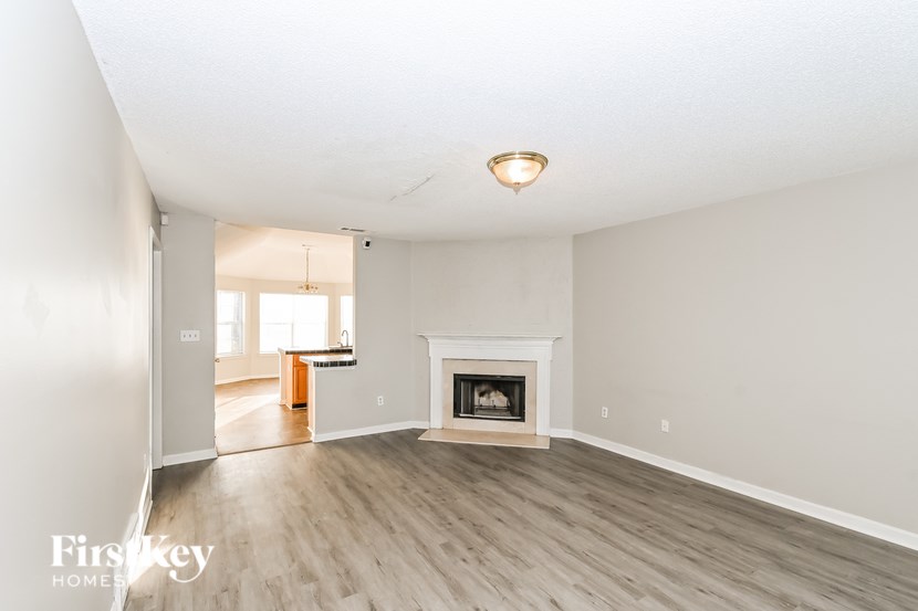 A large, empty room with a fireplace and wooden floors.