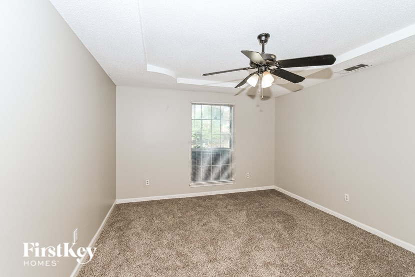 A room with a ceiling fan and a window with blinds.
