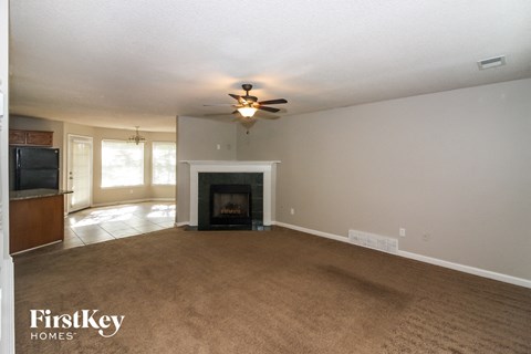 A living room with a fireplace and a ceiling fan.