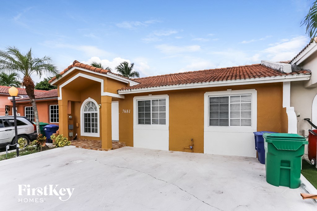 A yellow house with a red tile roof and a white garage door.