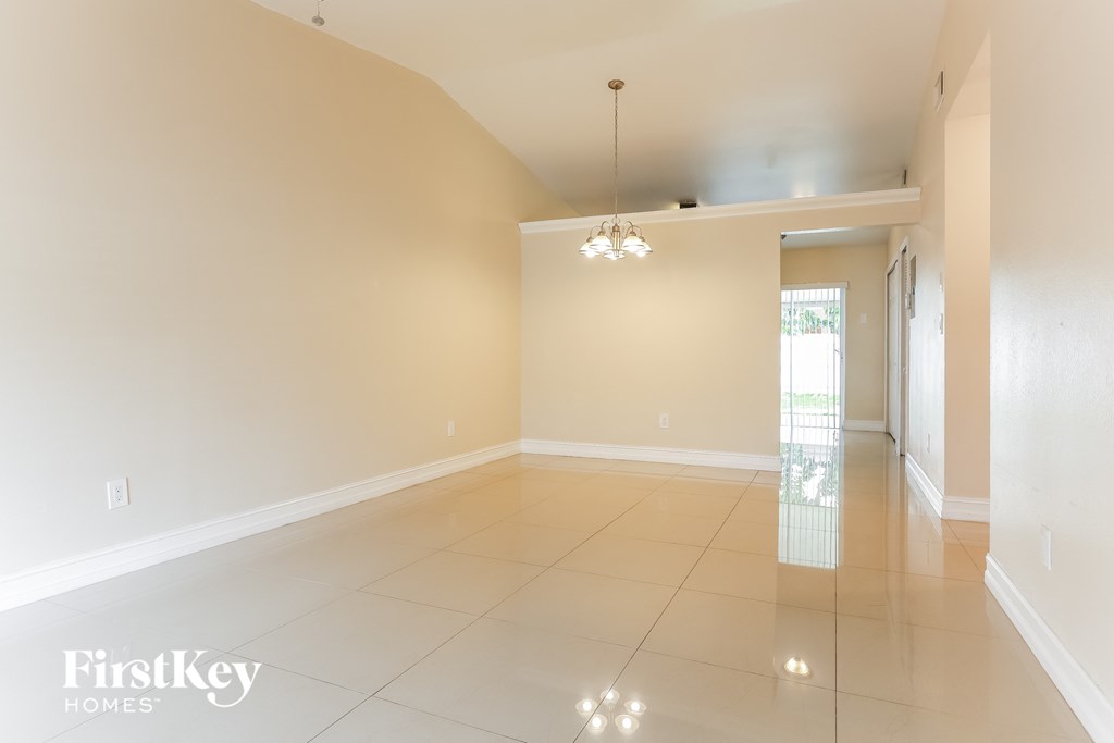 A spacious room with a chandelier and a door leading to a balcony.