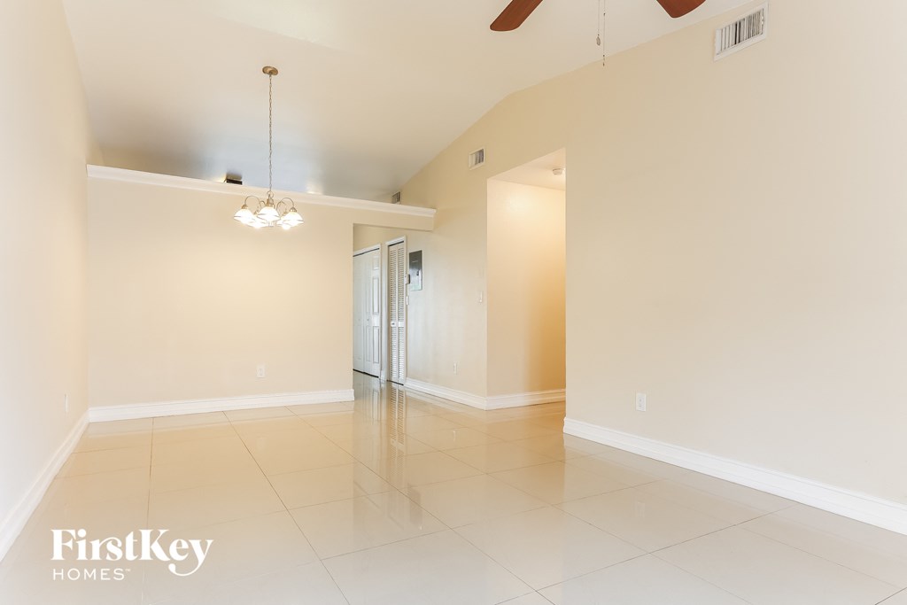 A spacious room with a ceiling fan and a chandelier.