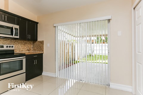 A kitchen with black cabinets and a white microwave.
