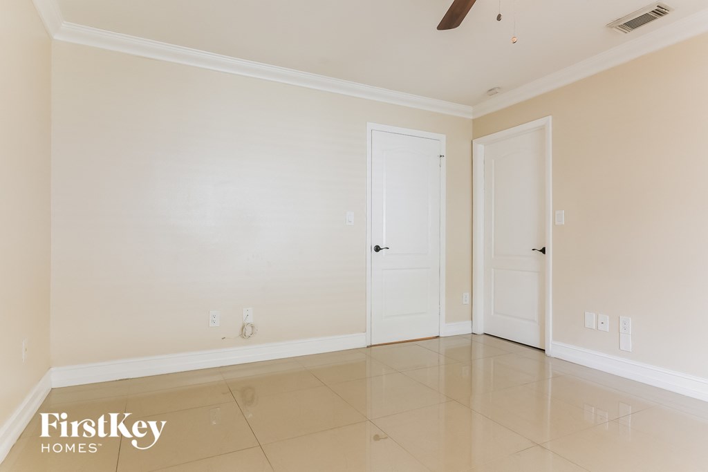 A spacious room with two doors and a ceiling fan.