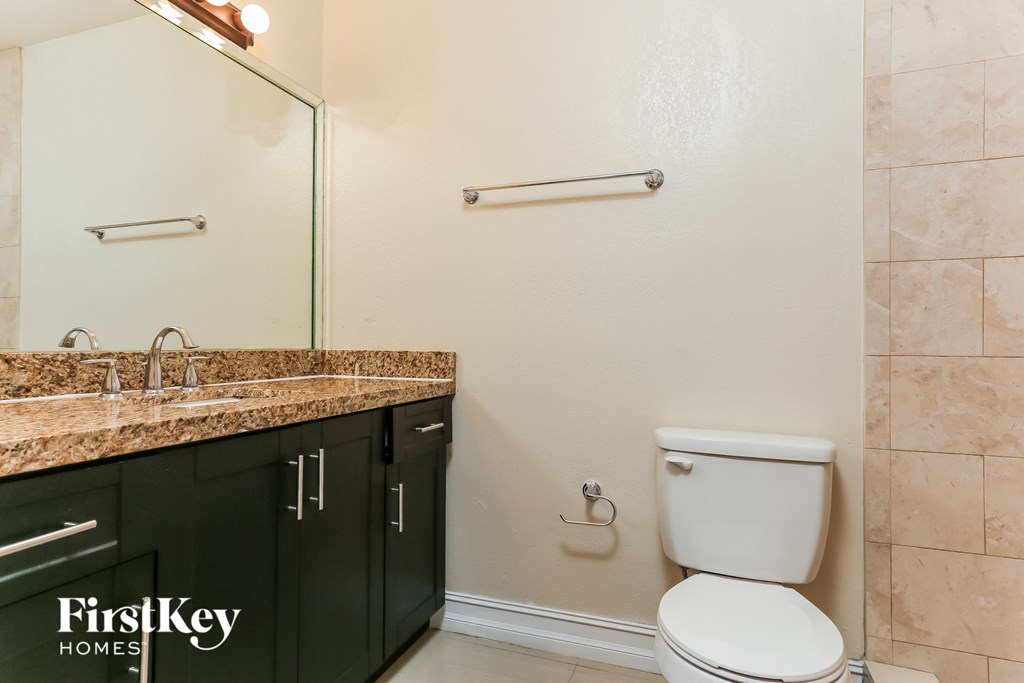 A bathroom with a toilet, sink, and a mirror.
