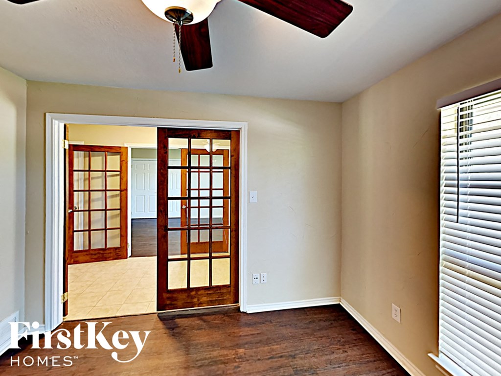 A room with a ceiling fan and a door leading to another room.