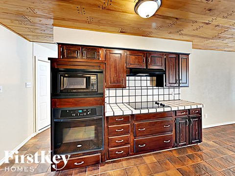 A kitchen with wooden cabinets and a black oven.