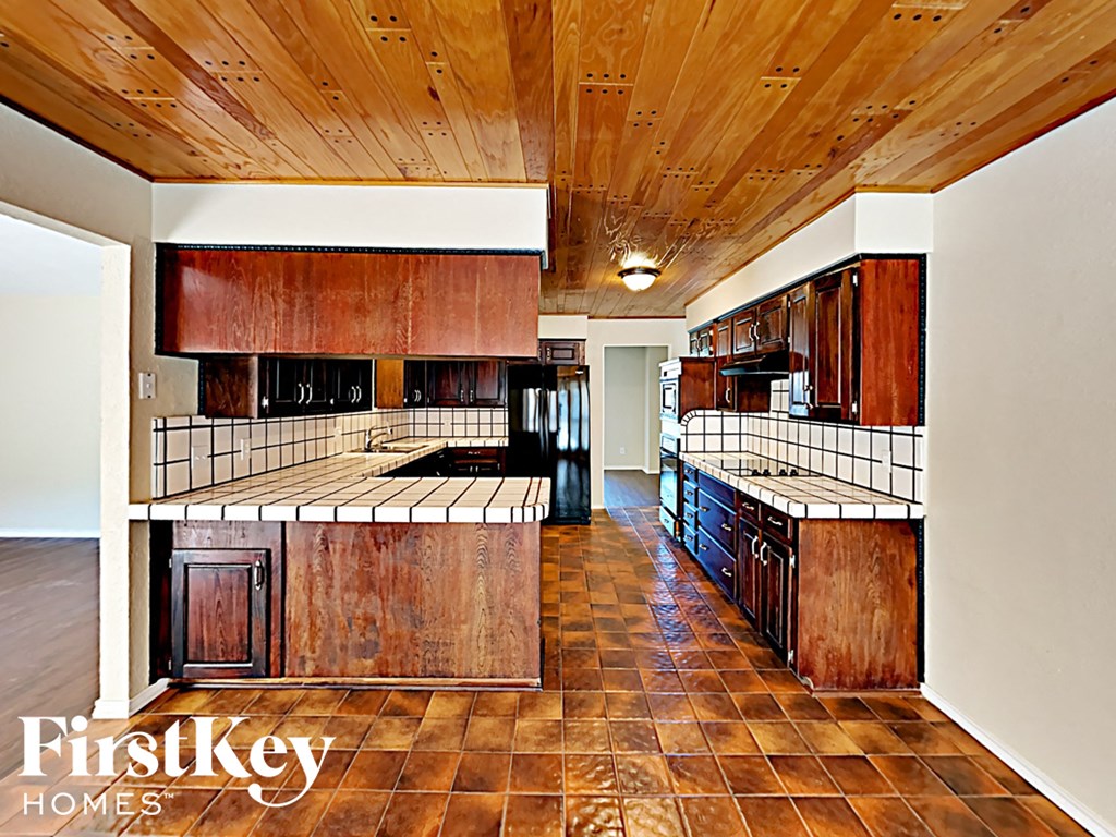 A kitchen with wooden cabinets and a tile floor.