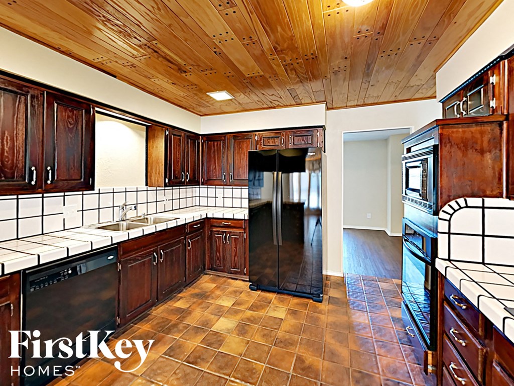A kitchen with wooden cabinets and a black fridge.