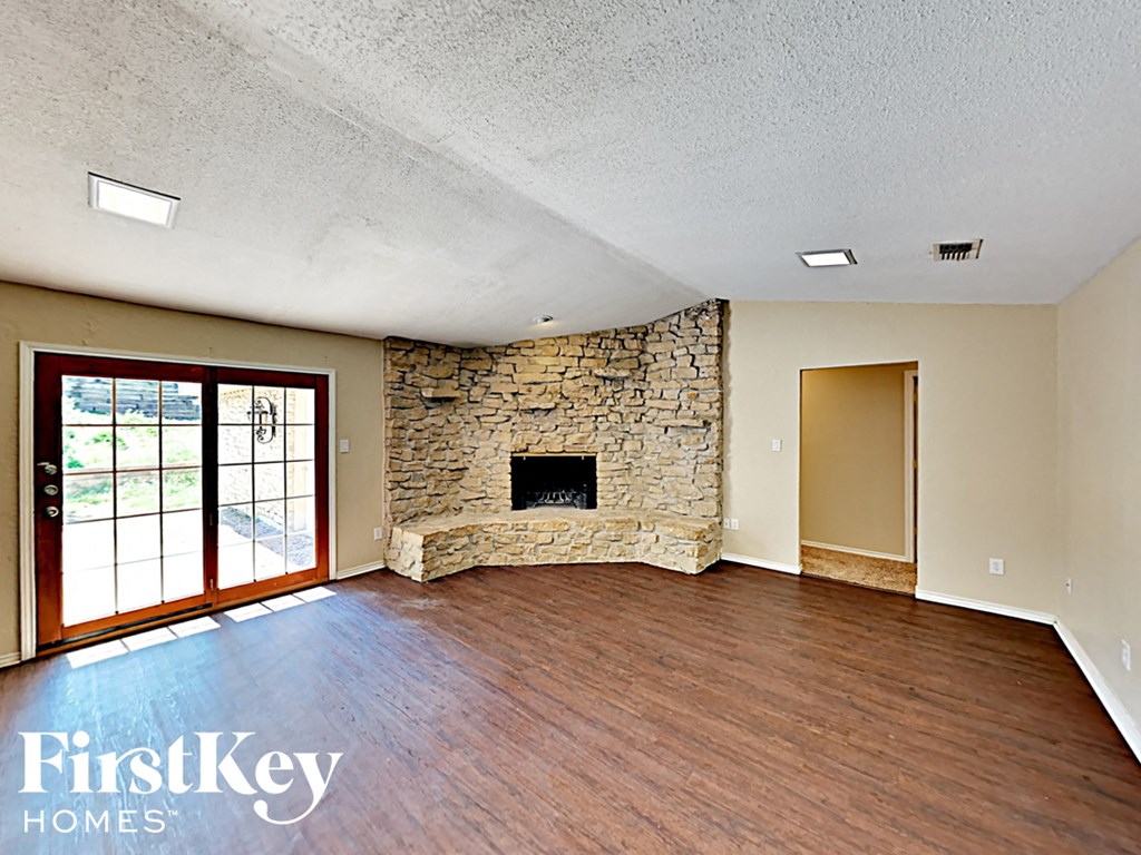 A room with a stone fireplace and wooden floors.