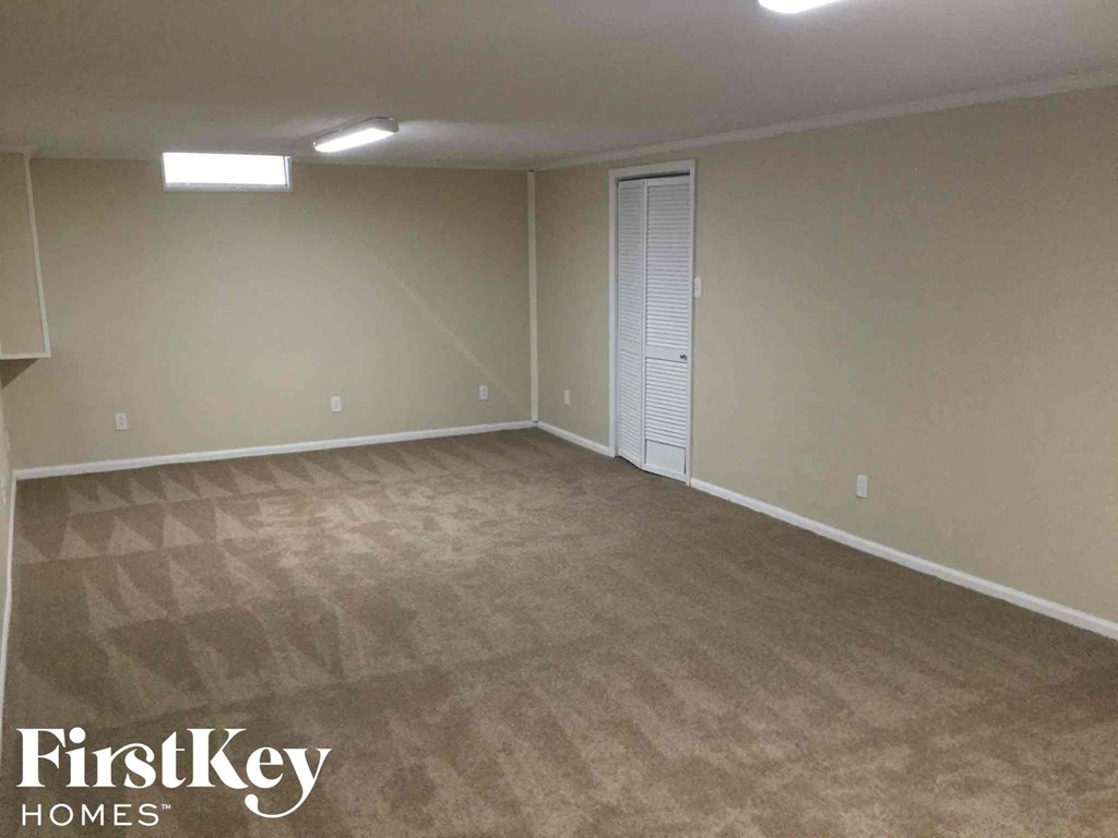 an empty living room with carpet and a door to a closet
