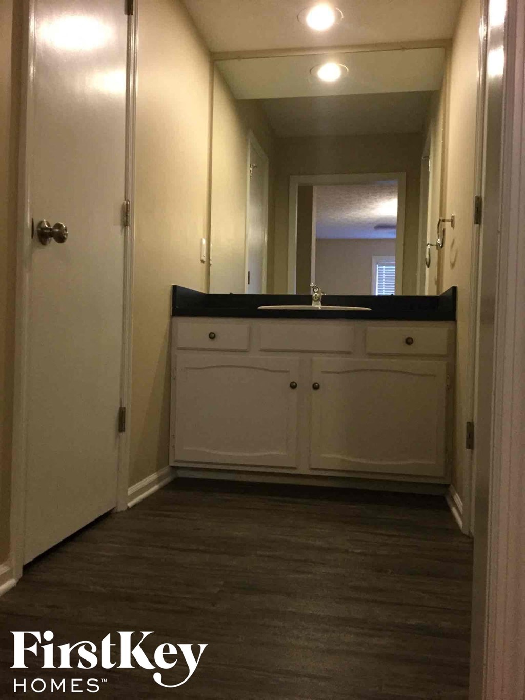 a small hallway with a sink and a mirror in a house