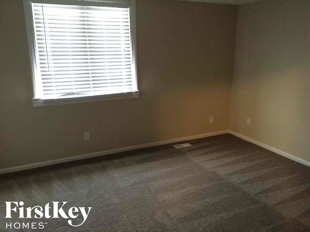 an empty room with a window and wood floors