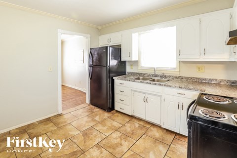 A kitchen with a black fridge and white cabinets.