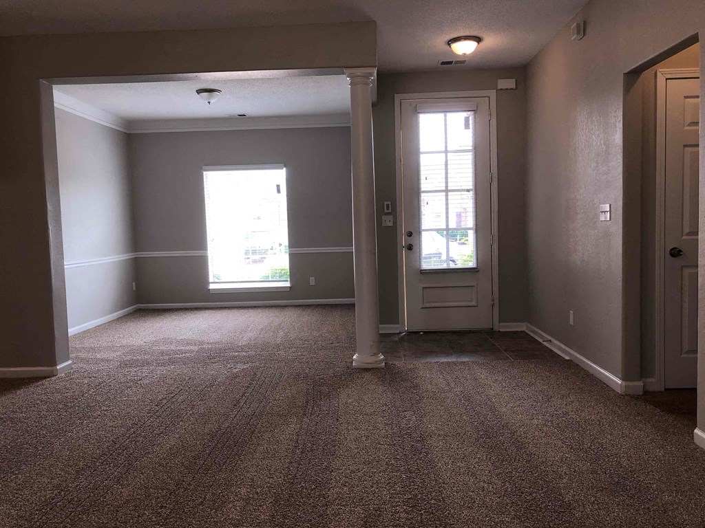 A room with a carpeted floor and a door.