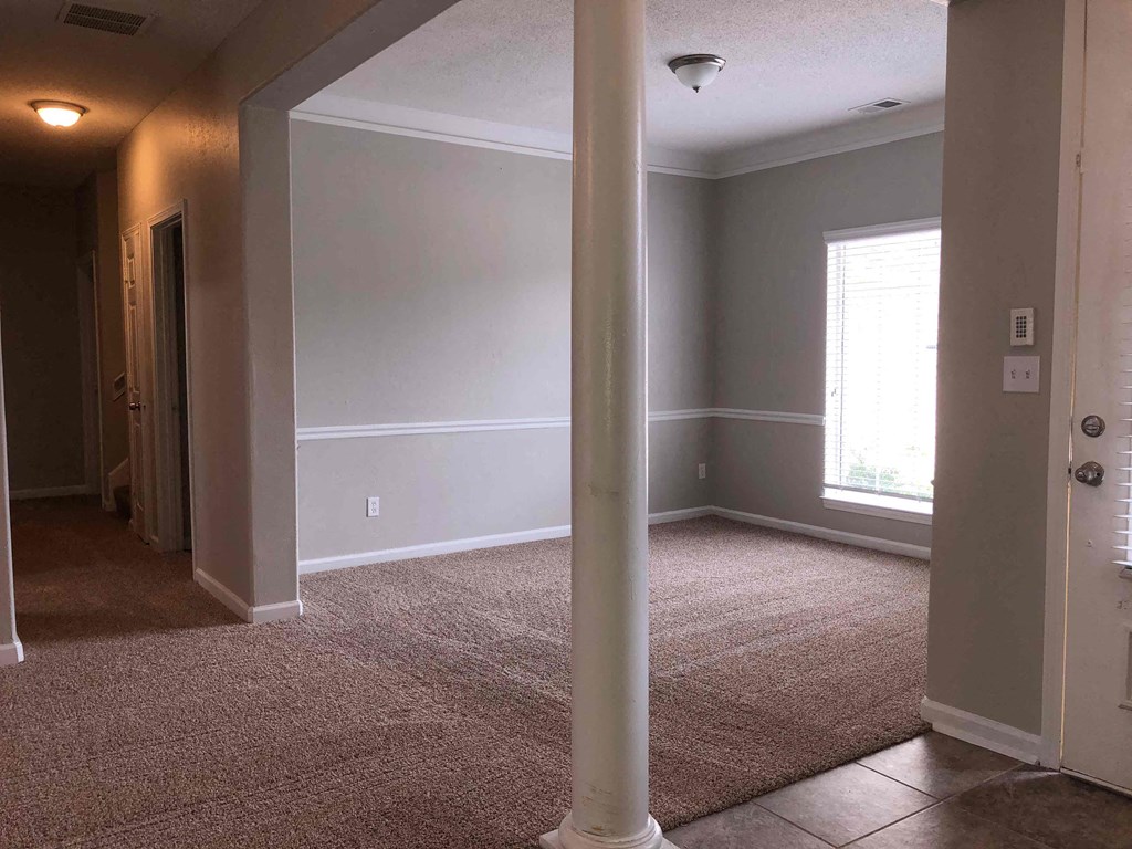 A room with a carpeted floor and a white pillar.