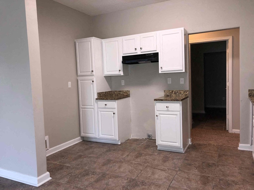 A kitchen with white cabinets and a granite countertop.